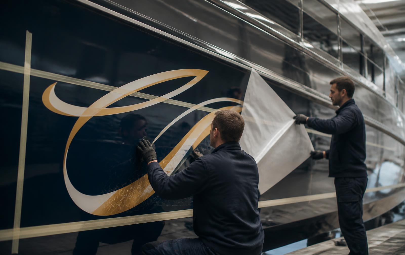 Anbringung eines individuellen Decals am Rumpf einer Yacht – Visualizzazione generata da IA
